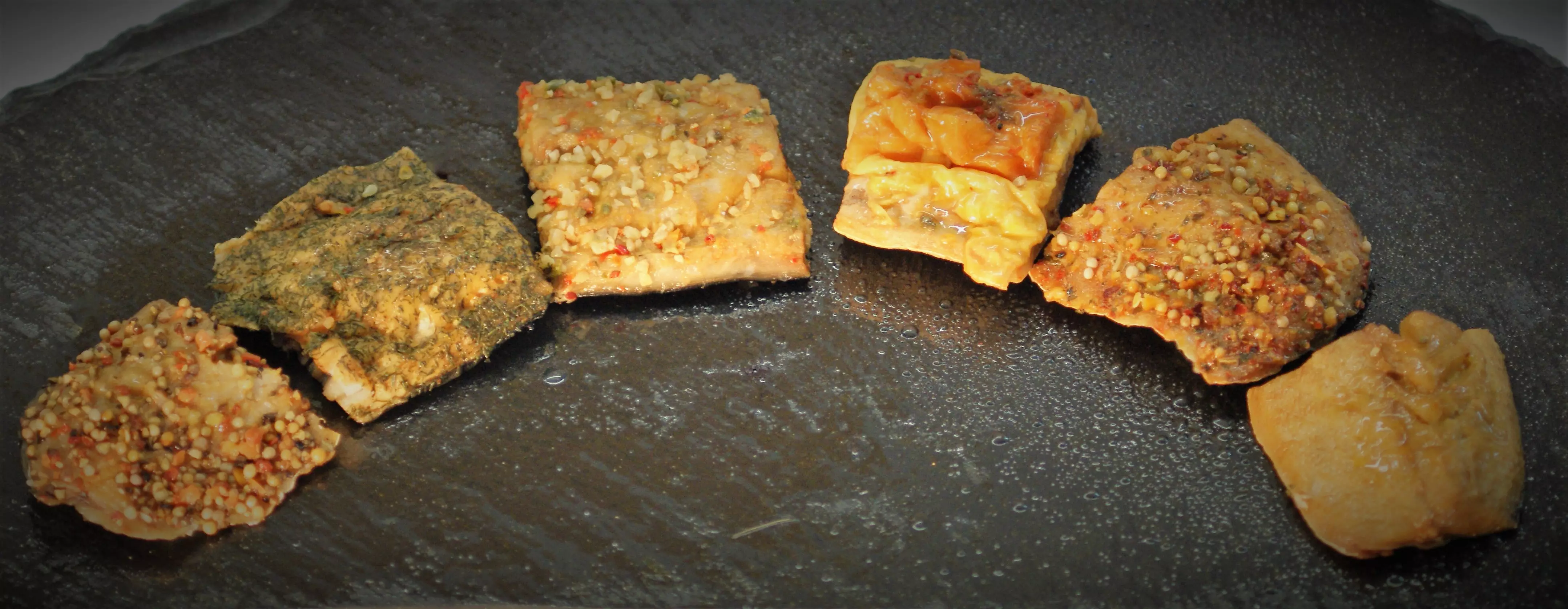 bunte marinierte Tofu Würfel auf dunklem Teller angeordnet