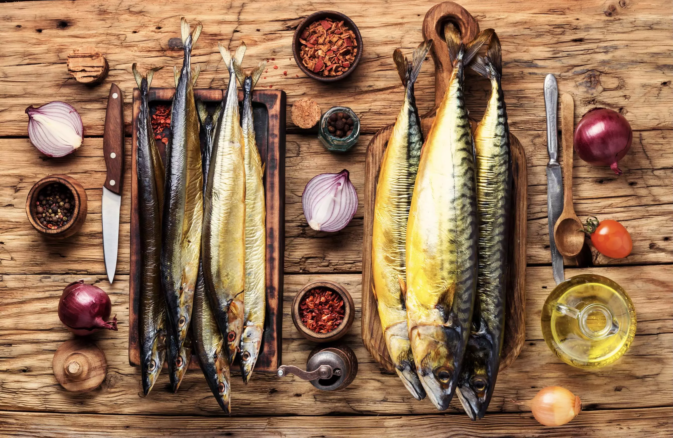 geräucherte Makrelen auf Holzbrett mit Zwiebeln und Gewürzen
