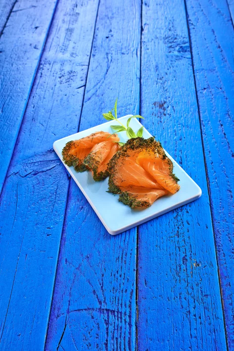 drei Scheiben Graved Lachs in Kräuterkruste auf weißem Telle