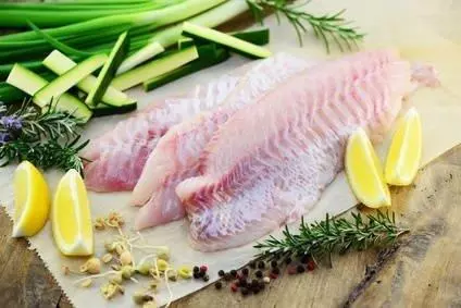 rohes Seelachsfilet mit Zitronenspalten und Gemüse auf Papie