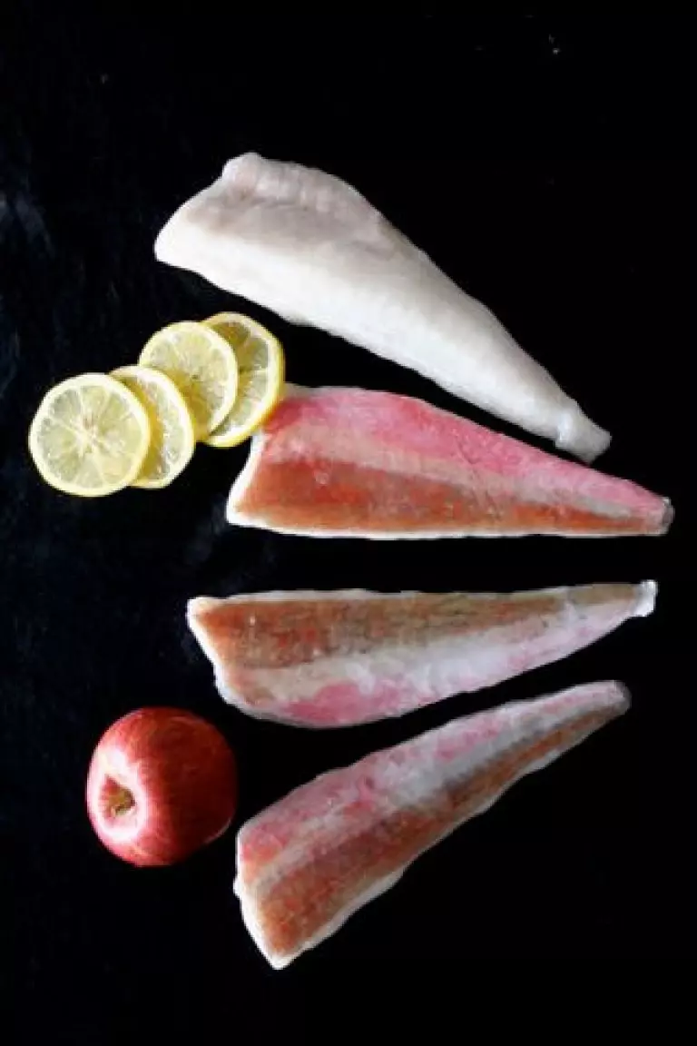 vier gefrorene Rotbarschfilets mit Zitrone und Apfel auf dun