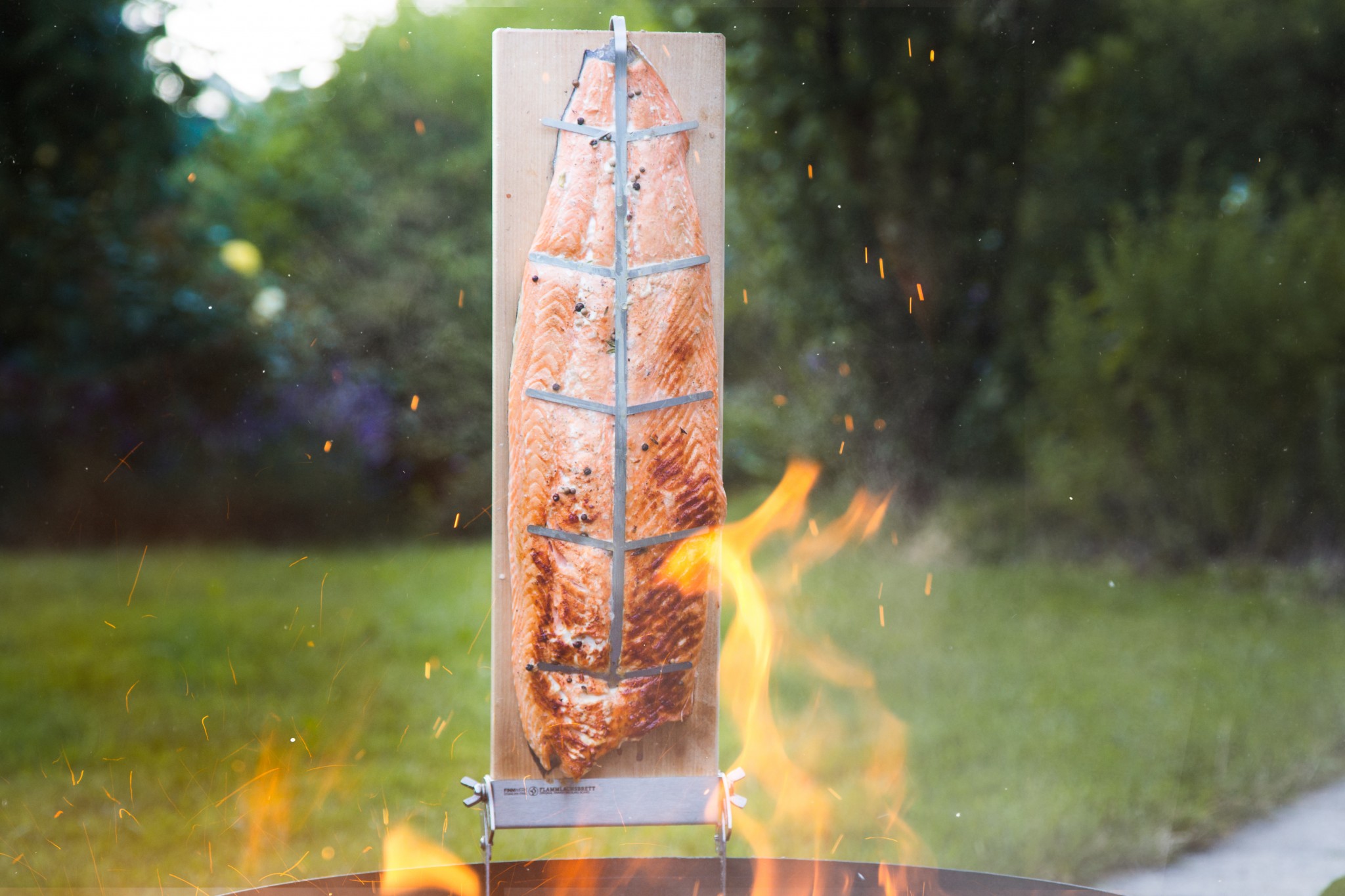 gegrilltes Lachsfilet auf Holzbrett über offenem Feuer