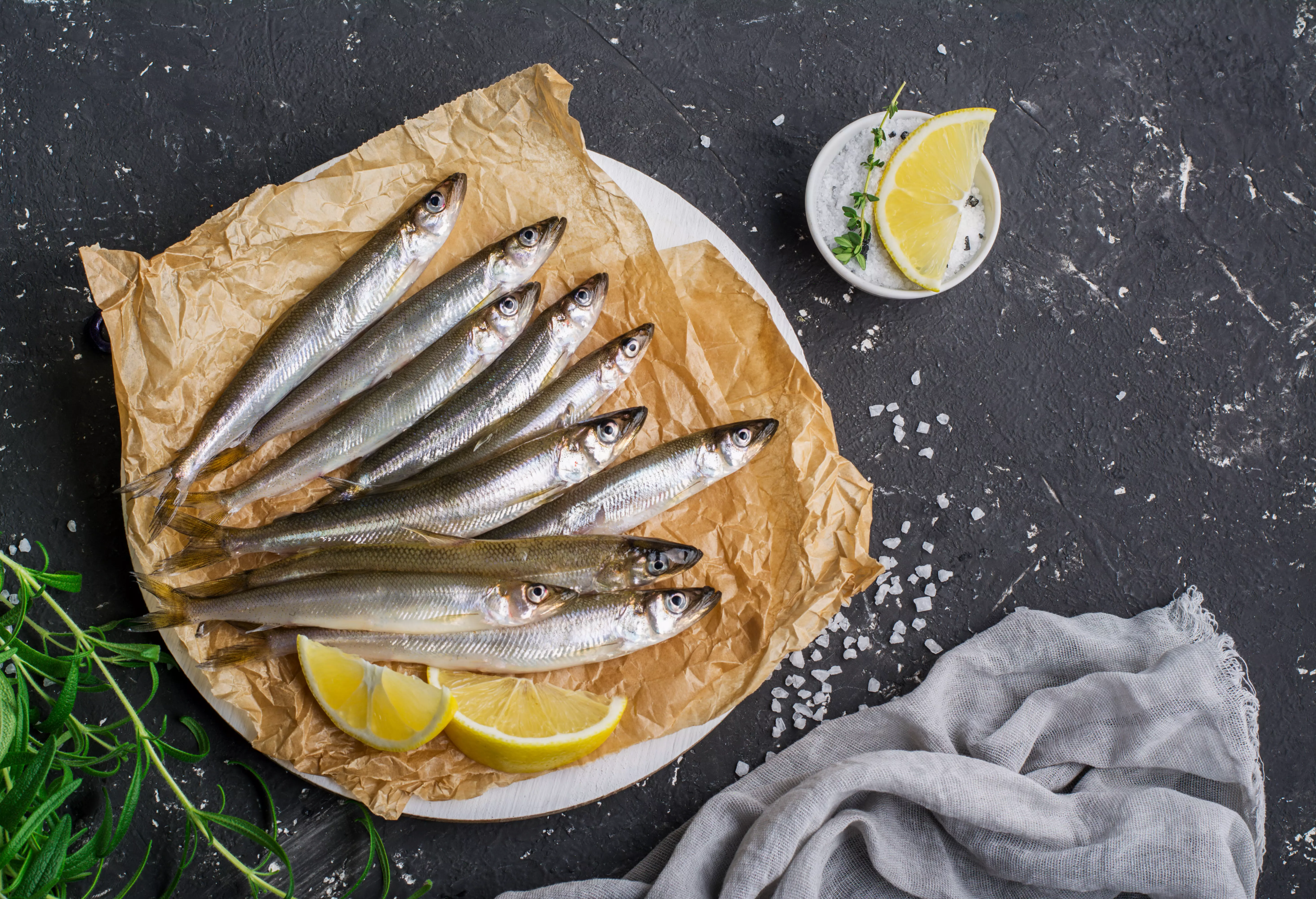 Rohe Sprotten auf Papier mit Zitronenscheiben arrangiert