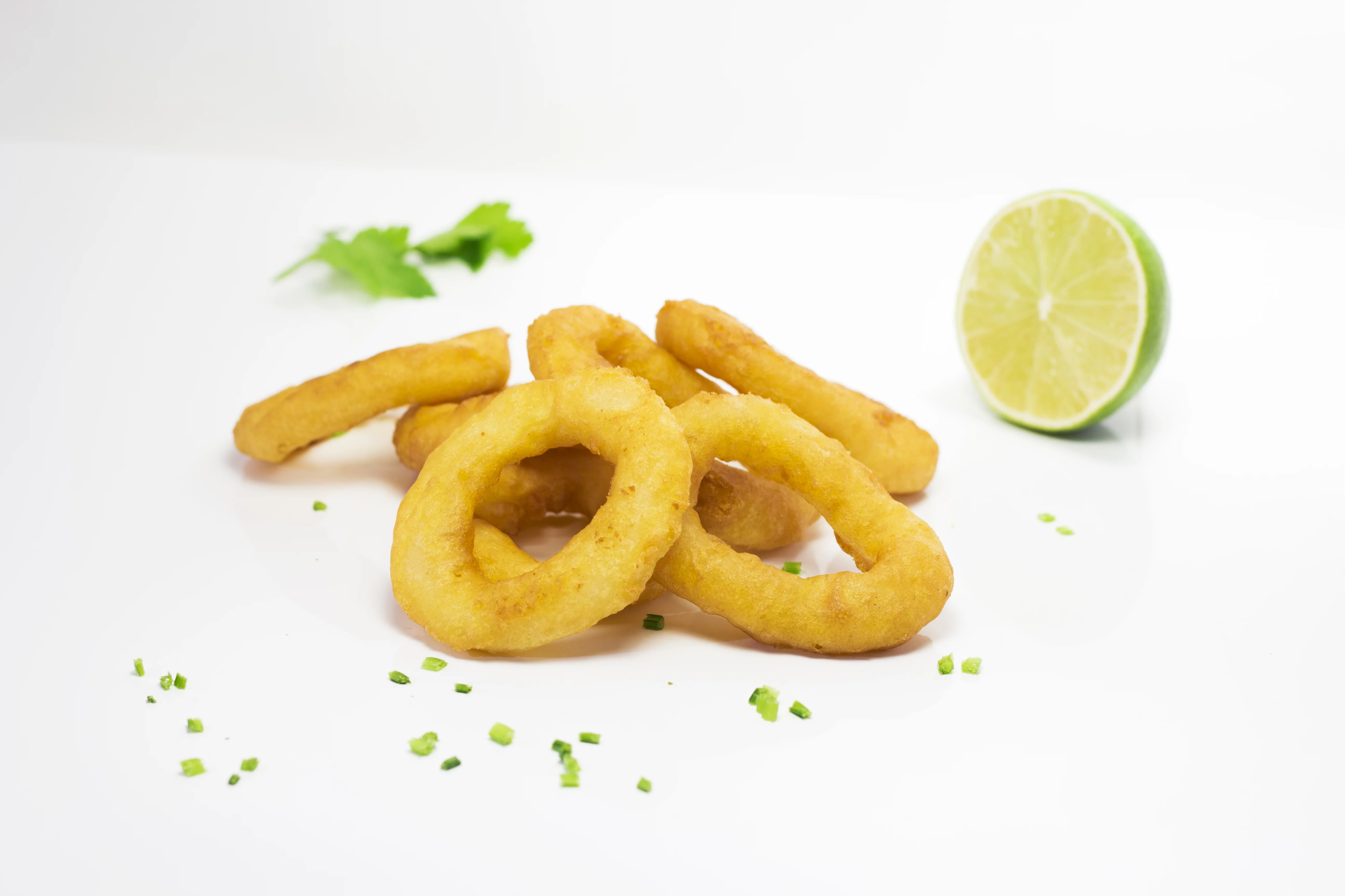 Goldene Zwiebelringe, serviert mit Limette, auf Weiß